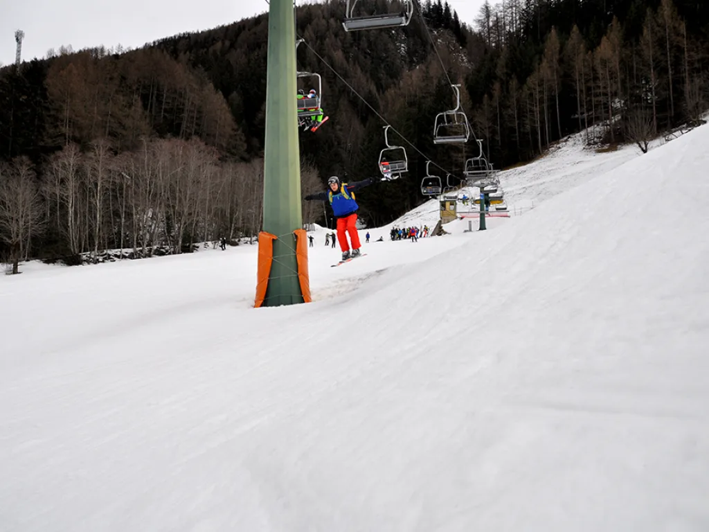 Skifahrerin in roter Hose auf dem Hang neben der Stütze.